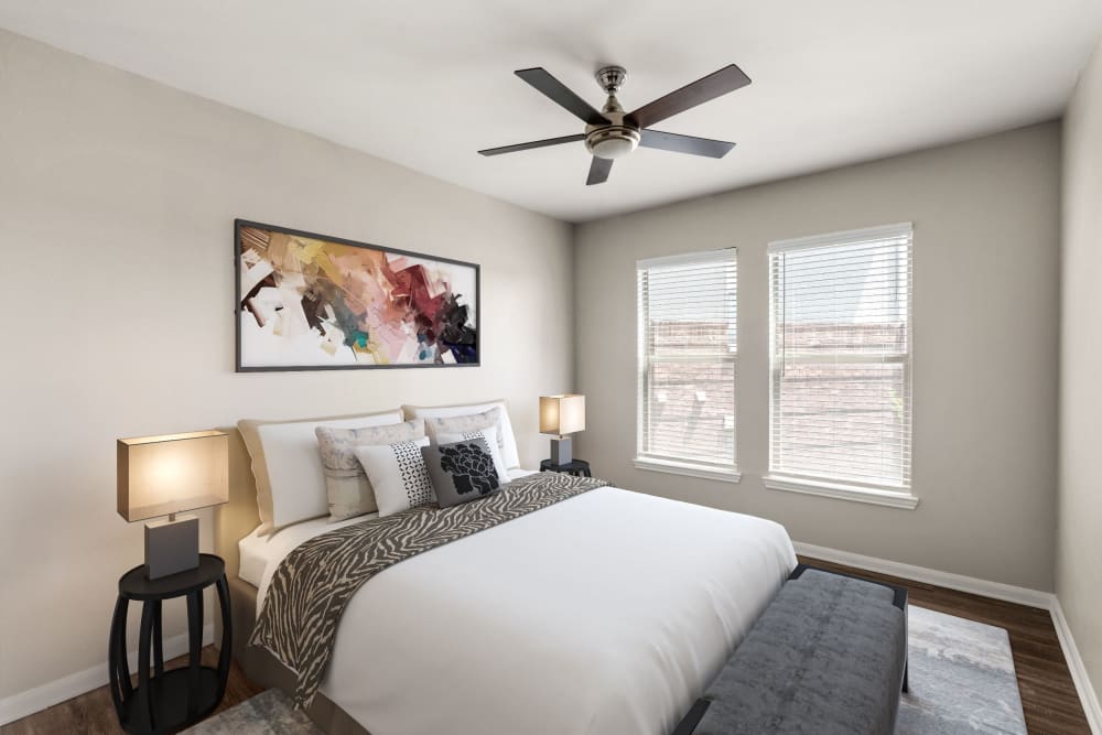 Model apartment's primary bedroom with wooden floor at Olympus Las Colinas in Irving, Texas
