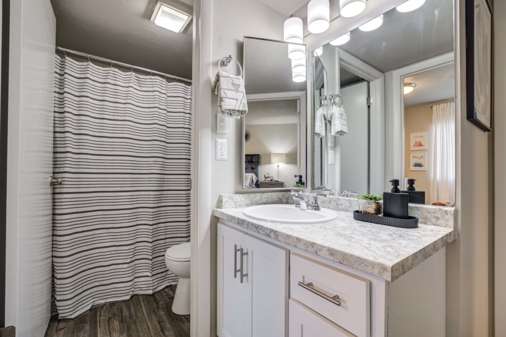 Bathroom with large vanity mirror at Cherry Creek Apartments in Riverdale, Utah