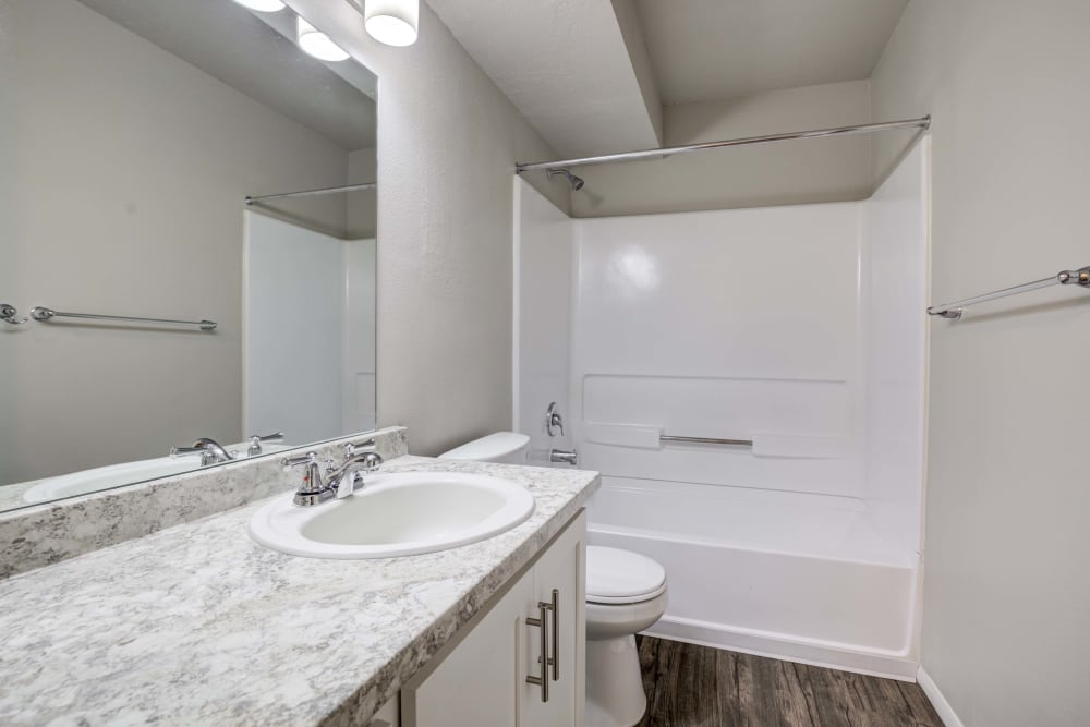 Bathroom with white stone countertop and shower tub at Cherry Creek Apartments in Riverdale, Utah