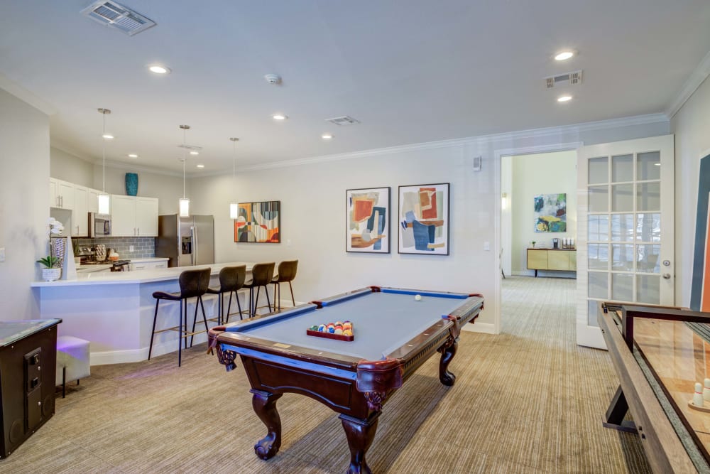Clubhouse game room  at Signature Point Apartments in League City, Texas features shuffleboard, billiards table and other activities for community members