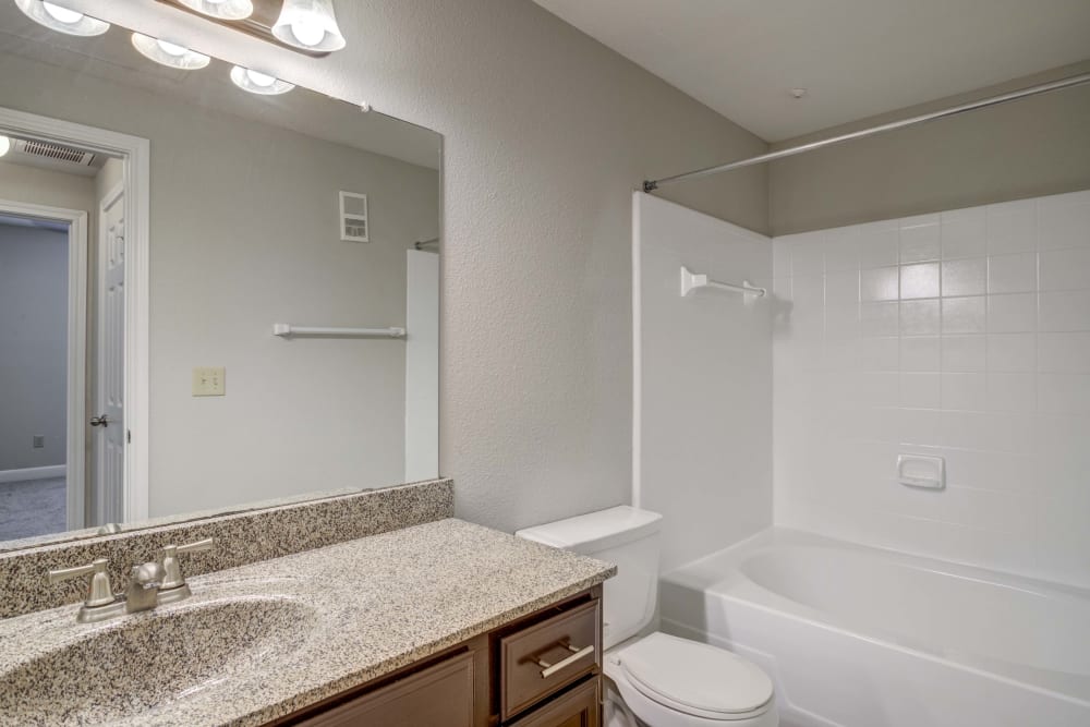 Bathroom with wood cabinets and white shower tub at Signature Point Apartments in League City, Texas