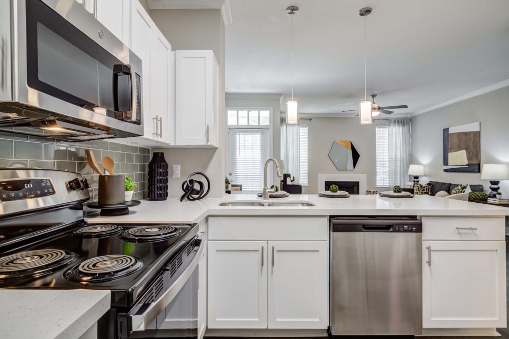 Kitchen with stainless steel appliances and white cabinets at Signature Point Apartments in League City, Texas