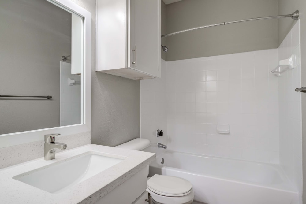 Bathroom with large vanity mirror and shower tub at Signature Point Apartments in League City, Texas