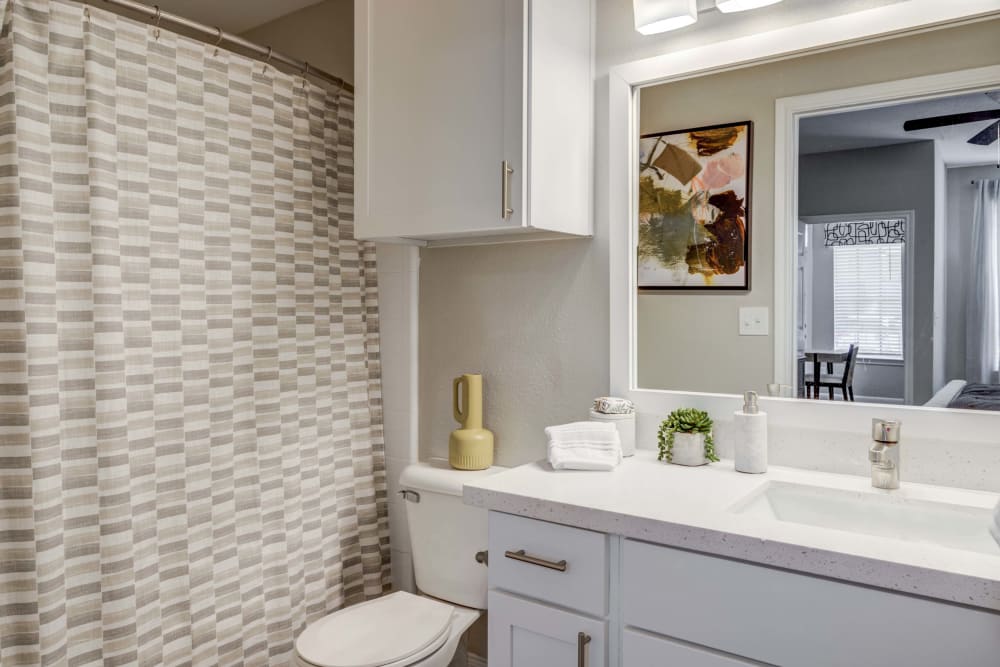 Bathroom featuring white cabinets and large vanity mirror at Signature Point Apartments in League City, Texas
