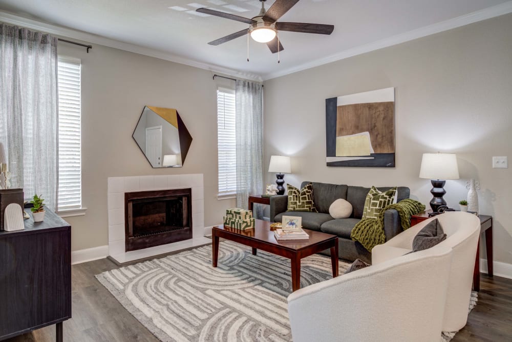 Living room with fireplace and ceiling fan at Signature Point Apartments in League City, Texas.