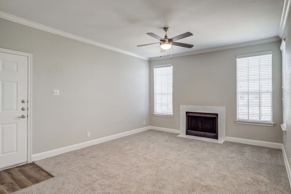 Apartment entrance into living room which features a ceiling, fan and fireplace at Signature Point Apartments in League City, Texas