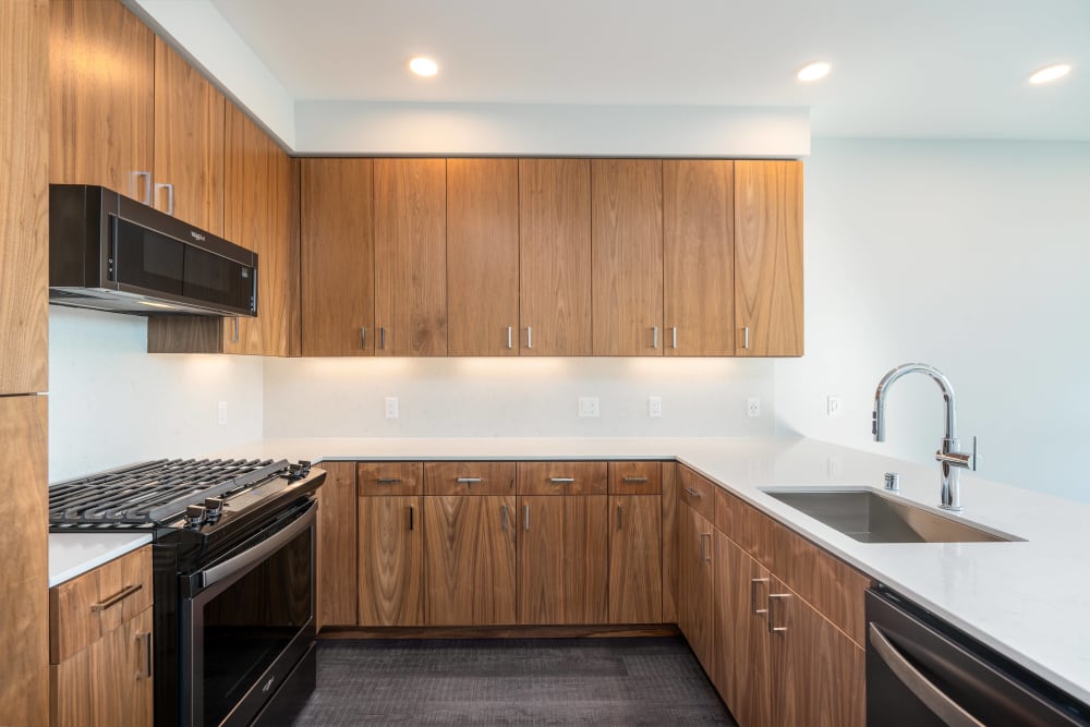 Penthouse kitchen with woodgrain cabinetry and gas range at MV Apartments in Mountain View, California