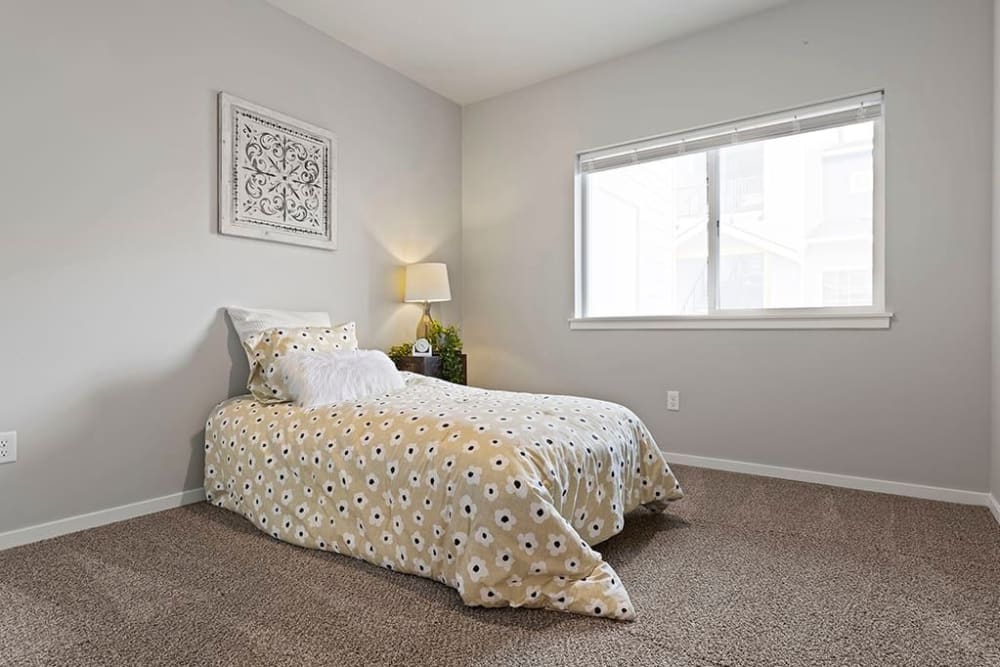 Model second bedroom with large windows at Wyndstone Apartments in Yelm, Washington