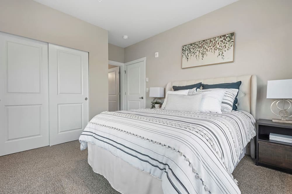 Master bedroom with closet and table lamp at Wyndstone Apartments in Yelm, Washington