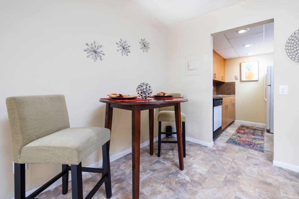 A square dining room table and chairs next to the kitchen in an apartment at Forest Place in North Miami, Florida