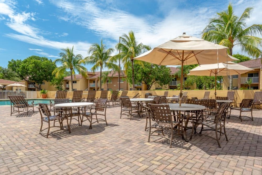 Patio seating with umbrellas near the swimming pool at Fairway View in Hialeah, Florida