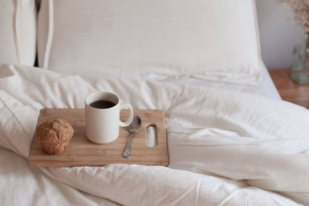 A well-made bed with a tray holding a coffee mug and muffin at Marina Del Mar in Sunny Isles Beach, Florida