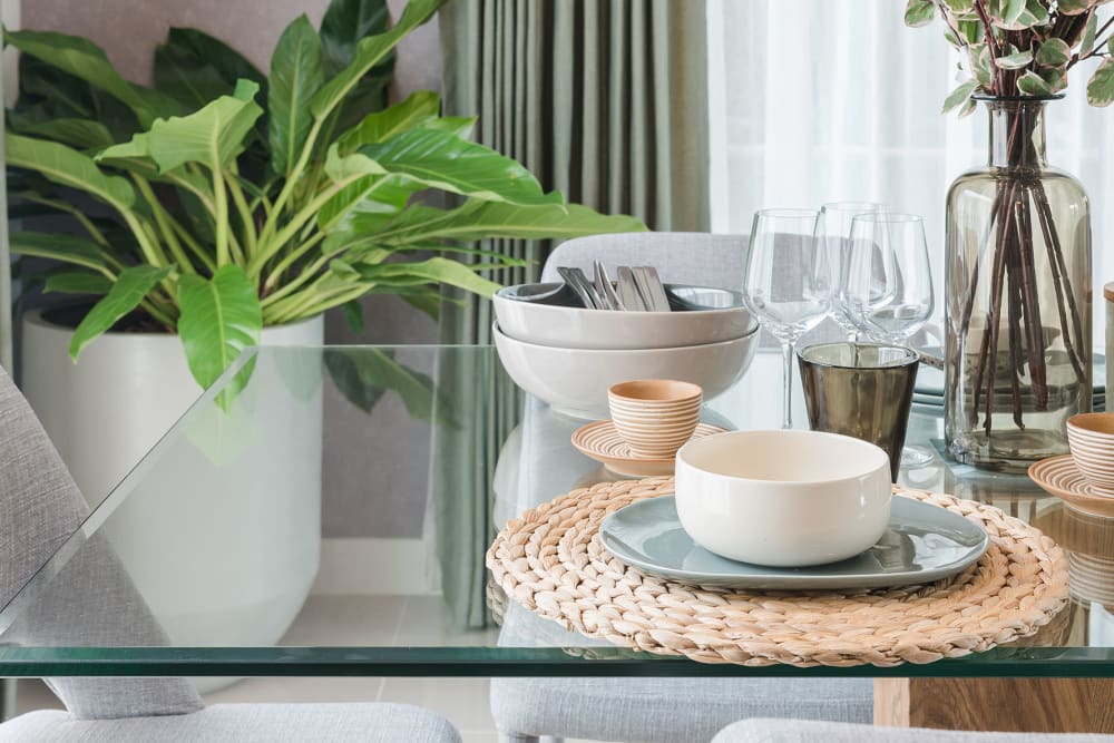 A glass dining room table set with dinnerware at Marina Del Mar in Sunny Isles Beach, Florida