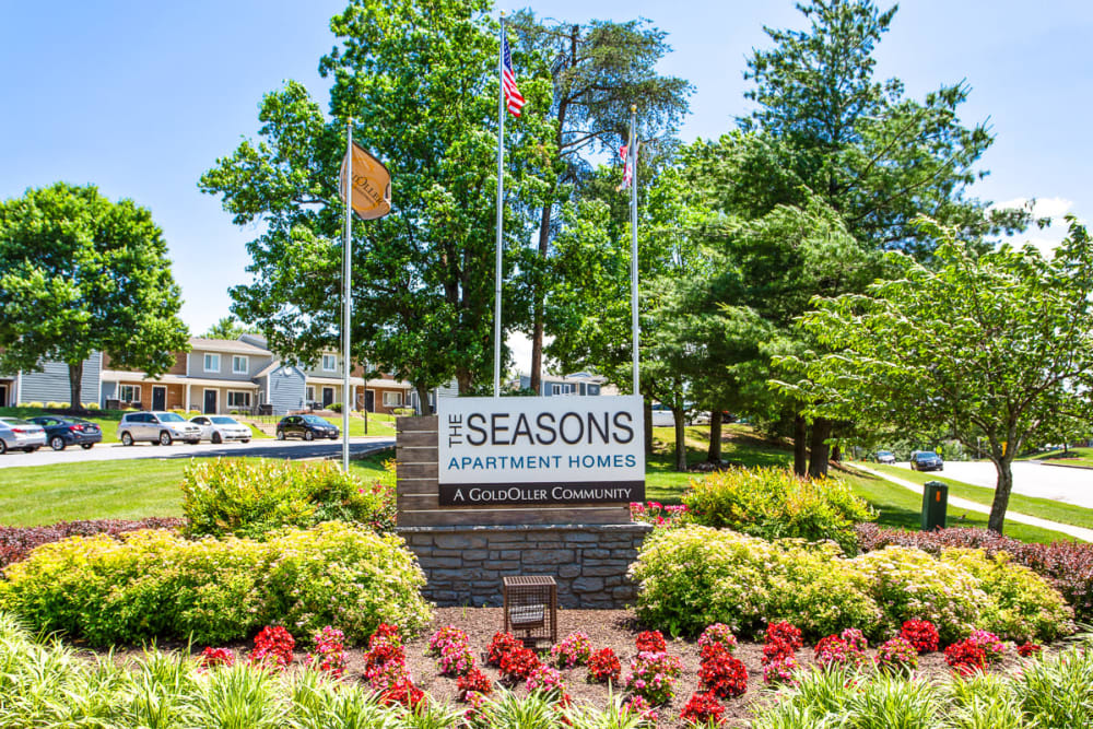 Entrance sign with flowers at The Seasons Apartments in Laurel, Maryland