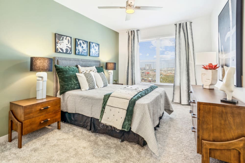 Spacious bedroom with carpet, ceiling fan, and large windows  at The Margaret at Riverfront in Dallas, Texas