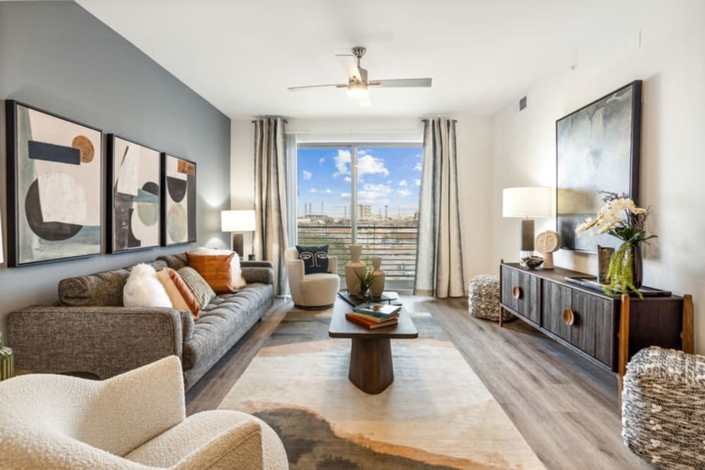 Living room with balcony, wood-style flooring, ceiling fan, and views of Downtown Dallas at The Margaret at Riverfront in Dallas, Texas