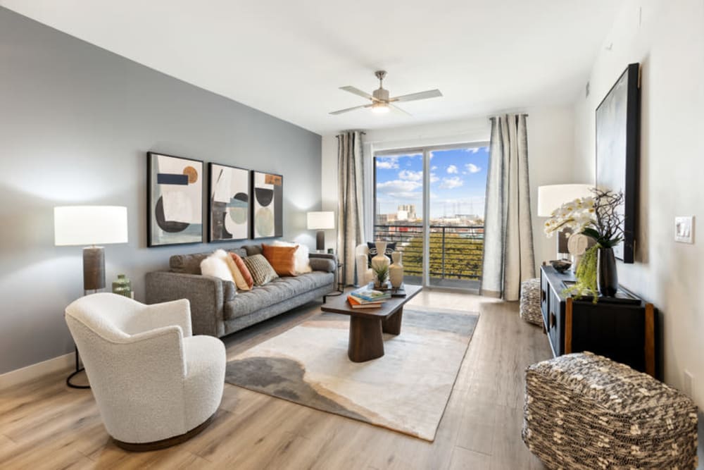 Living room with balcony, wood-style flooring, ceiling fan, and views of Downtown Dallas at The Margaret at Riverfront in Dallas, Texas