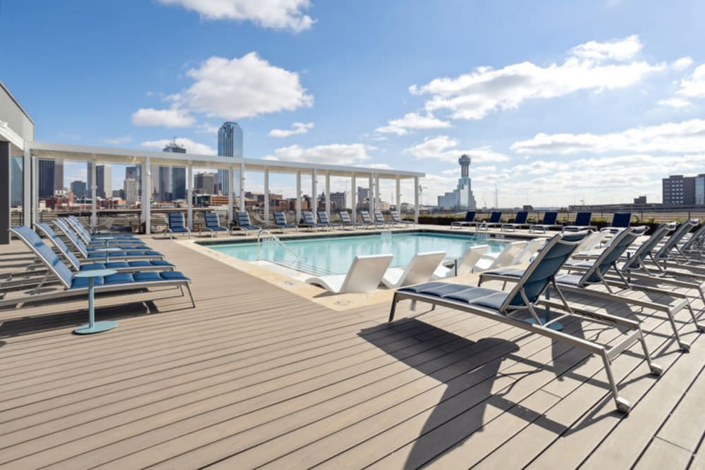 Rooftop pool with lounge chairs, grilling area, and views of Downtown Dallas at The Margaret at Riverfront in Dallas, Texas