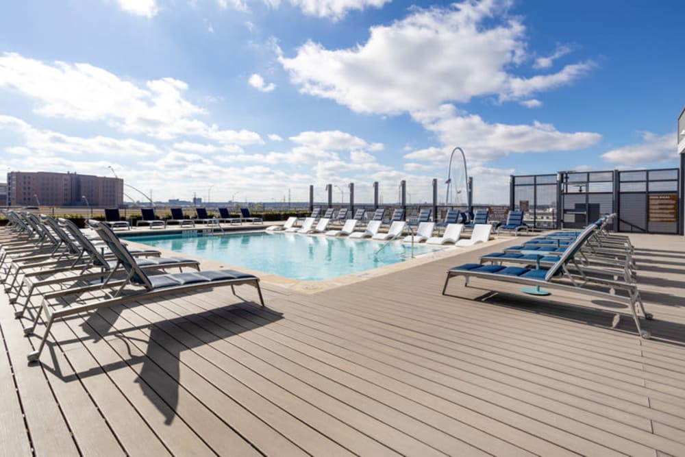 Rooftop pool with lounge chairs, grilling area, and views of The Margaret Hunt Hill Bridge in Downtown Dallas 