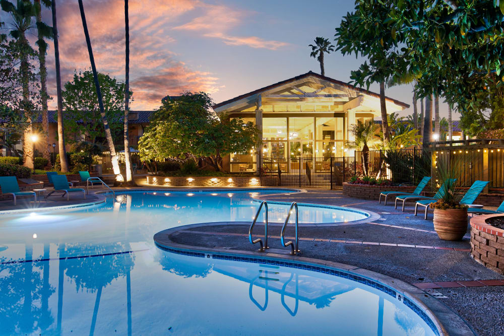 Resort style swimming pool at dusk at Mediterranean Village Apartments in Costa Mesa, California