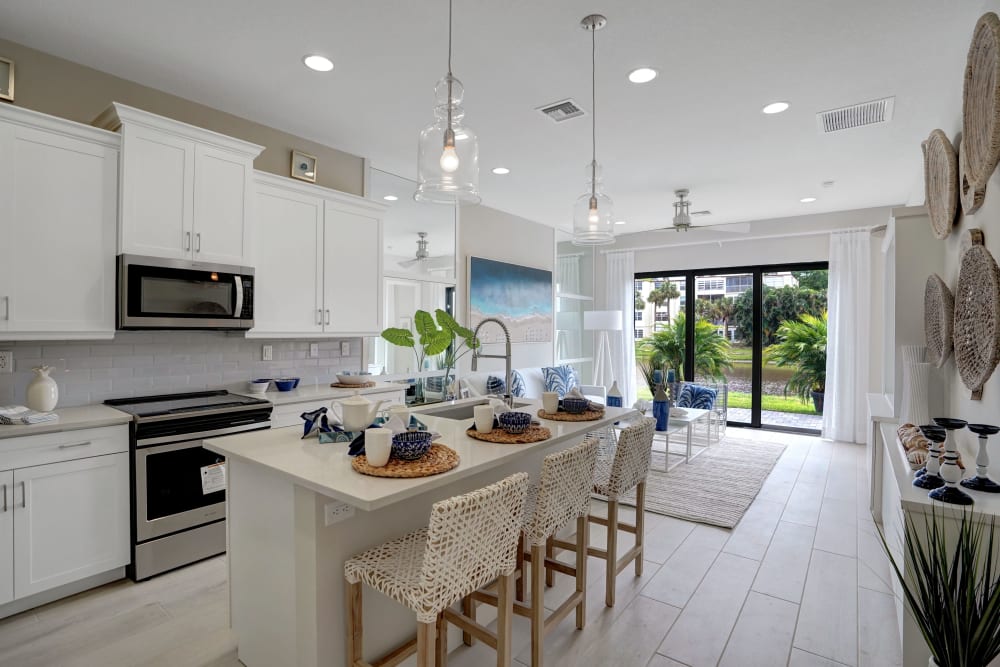 Eat-in kitchen with white cabinets and modern hanging light fixtures at Solera at Avalon Trails in Delray Beach, Florida