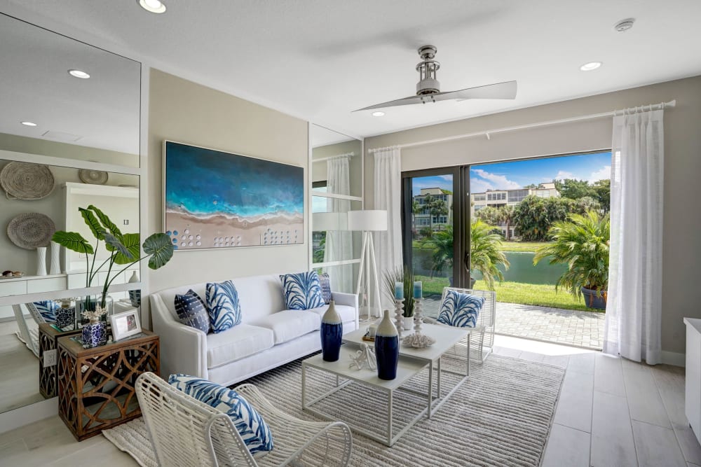 Apartment living room with sliding glass door to backyard at Solera at Avalon Trails in Delray Beach, Florida