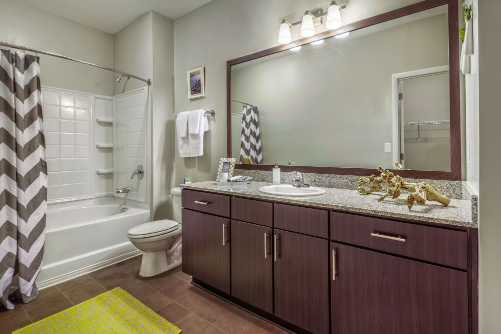 Wood flooring and dark wood cabinets in an apartment bathroom at South Ridge in Greenville, South Carolina