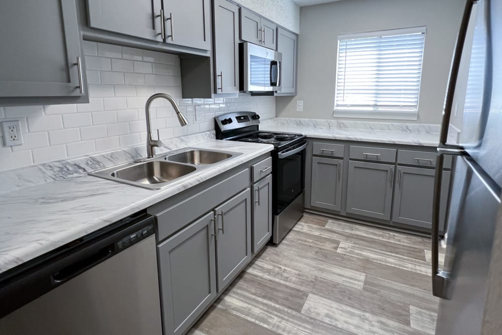 Dark painted cabinets and wood flooring in an apartment kitchen at Pinewood Station in Hillsborough, North Carolina