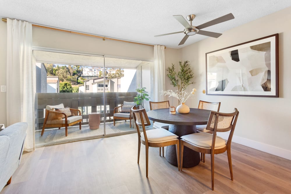 Bright dining room with a sliding glass door going out to a private balcony in a model home at The Villas at Woodland Hills in Woodland Hills, California 