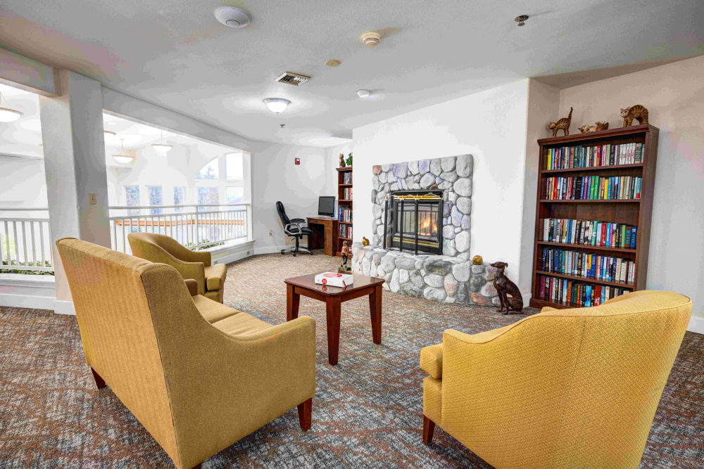 Cozy sitting area with a gas fireplace and bookshelf at Callahan Village Retirement  and Assisted Living in Roseburg, Oregon