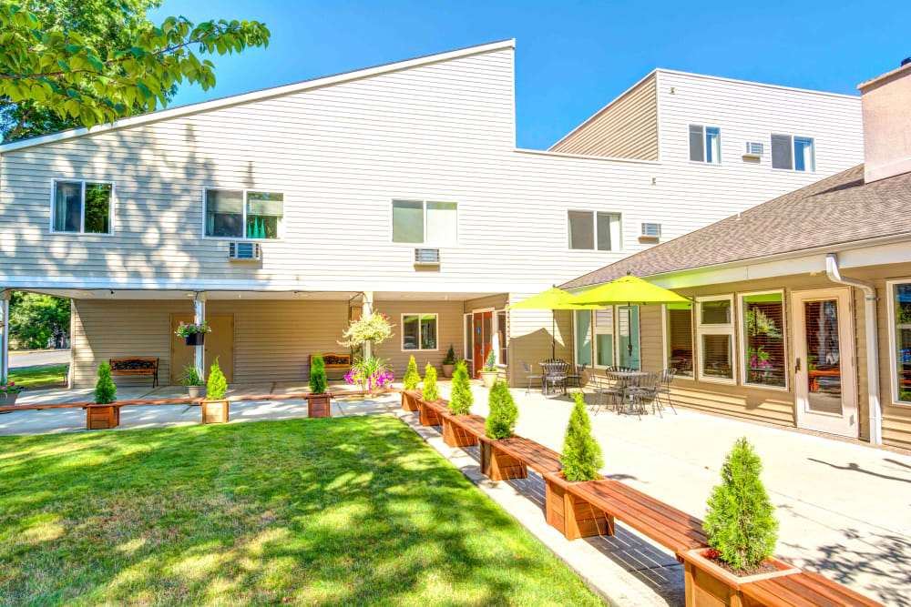 Courtyard with shaded patio tables and benches at Junction City Retirement and Assisted Living in Junction City, Oregon