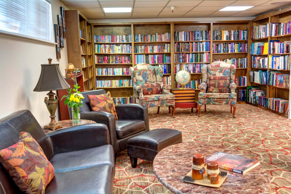 Library with walls lined with bookshelves and a sofa and armchair at Junction City Retirement and Assisted Living in Junction City, Oregon