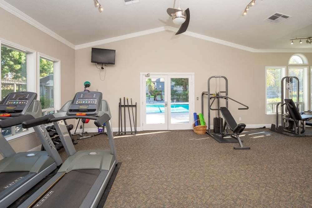 Modern gym fitness room with large windows and treadmills at Manchester Court in Modesto, California