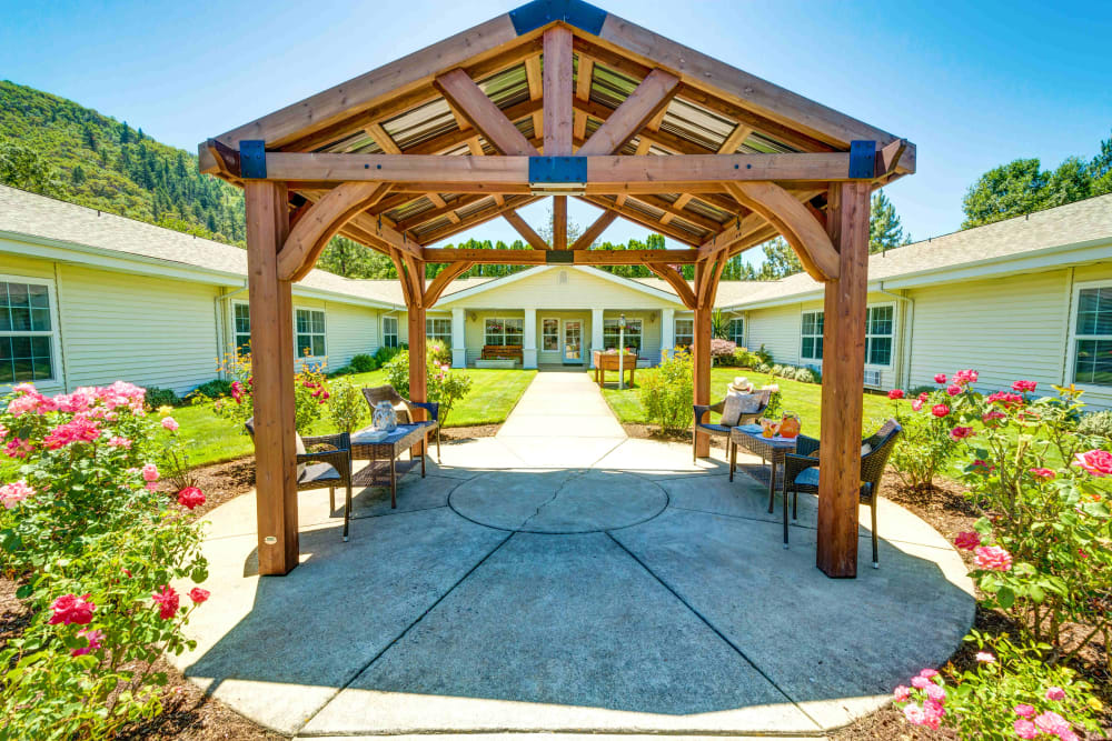 Pavilion with seating surrounded by roses in the courtyard at Morrow Heights Assisted Living in Rogue River, Oregon