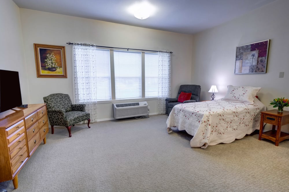 Bedroom and living space with large windows in a studio apartment at Hawks Ridge Assisted Living in Hood River, Oregon