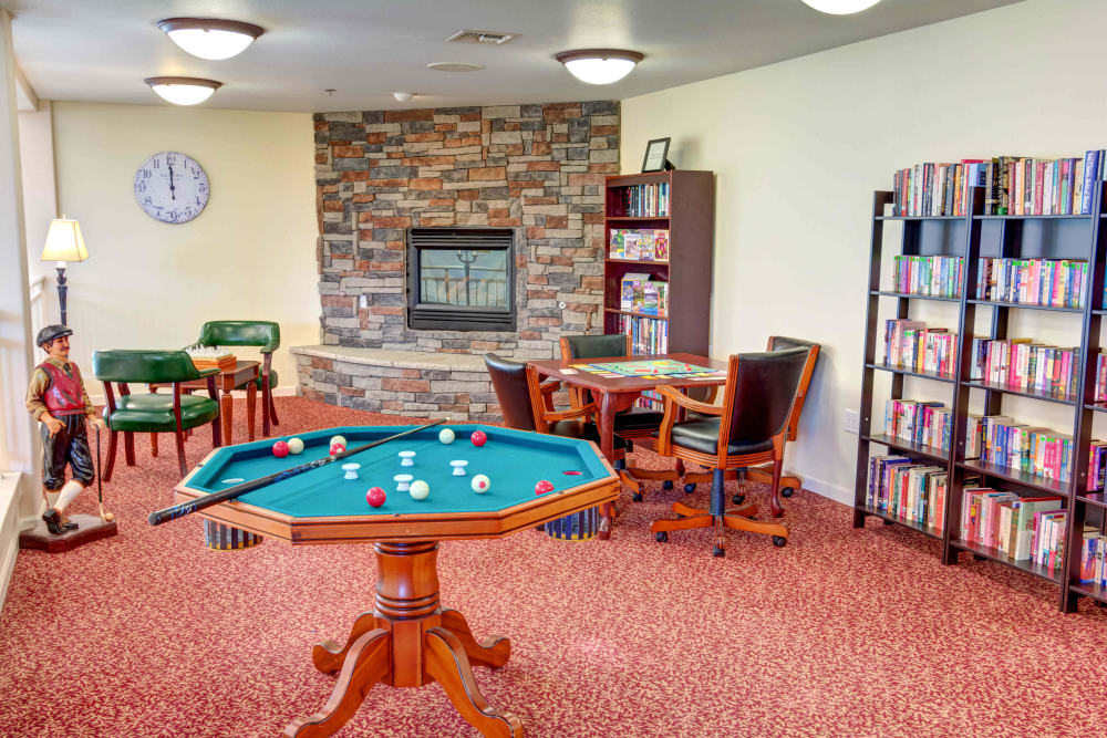 Entertainment room with bumper pool, a bookshelf, and a gas fireplace at Hawks Ridge Assisted Living in Hood River, Oregon