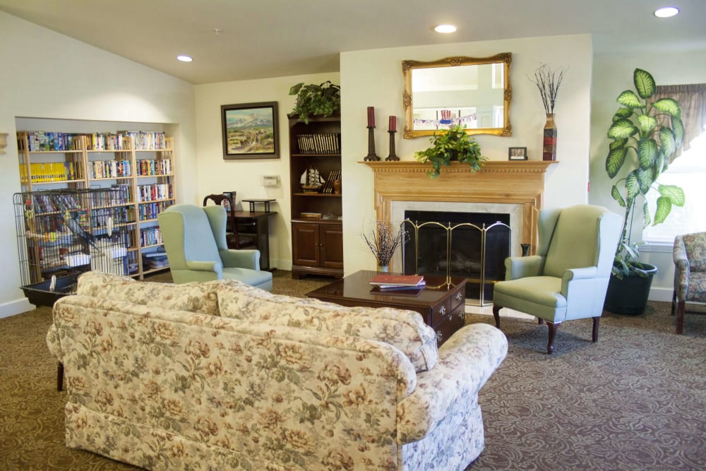 Comfortable resident lounge with a fireplace and bookshelf at Settler's Park Senior Living in Baker City, Oregon
