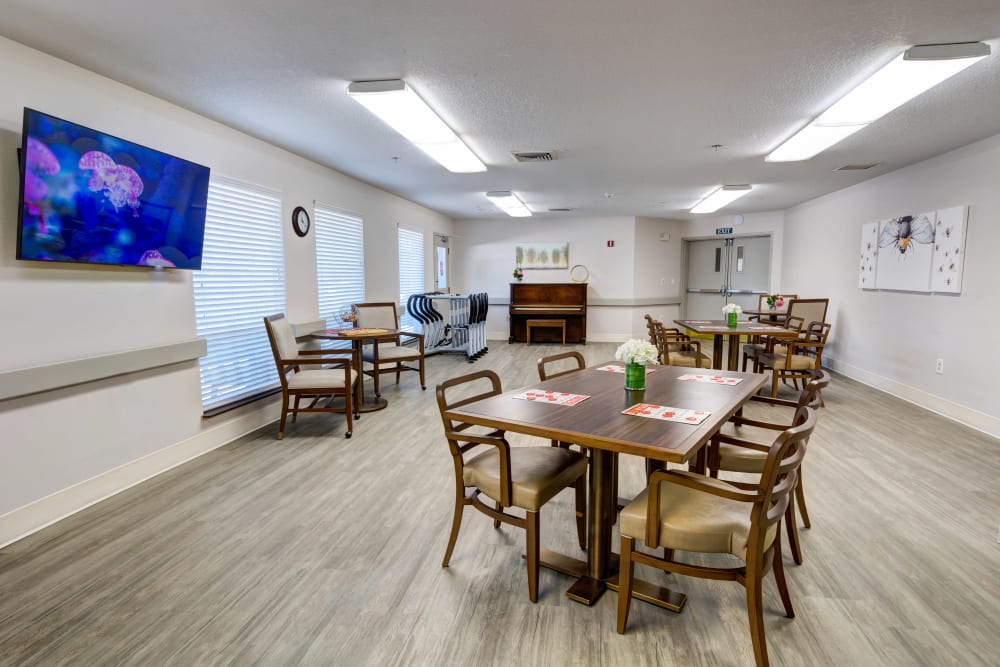 Entertainment room with game tables, a piano, and a TV at Silver Creek Senior Living in Woodburn, Oregon