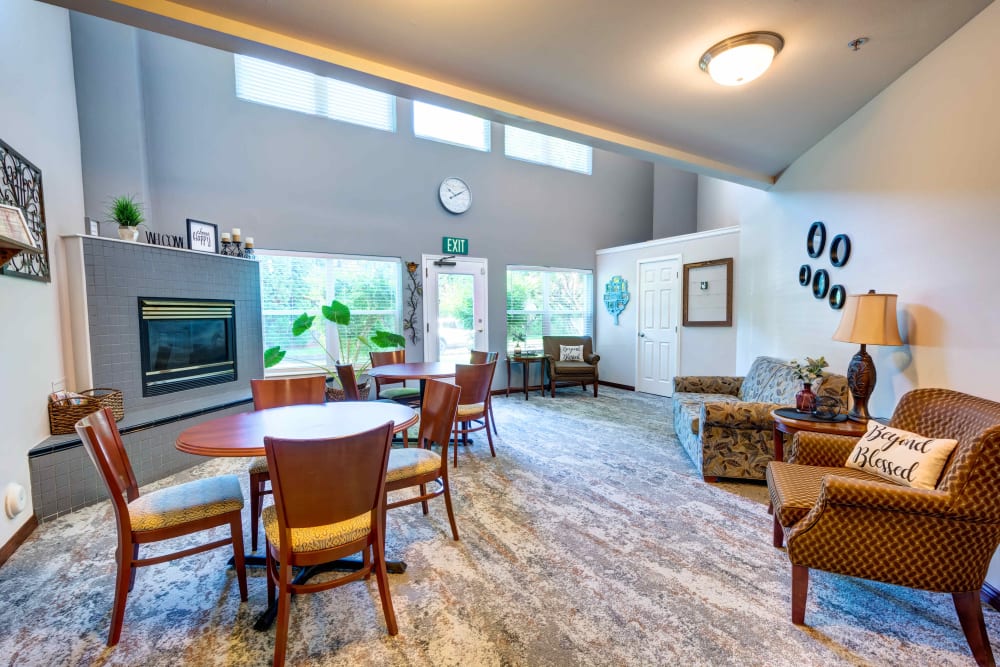 Comfortable sitting area with a gas fireplace and tables for games or gathering at The Suites Assisted Living and Memory Care in Grants Pass, Oregon