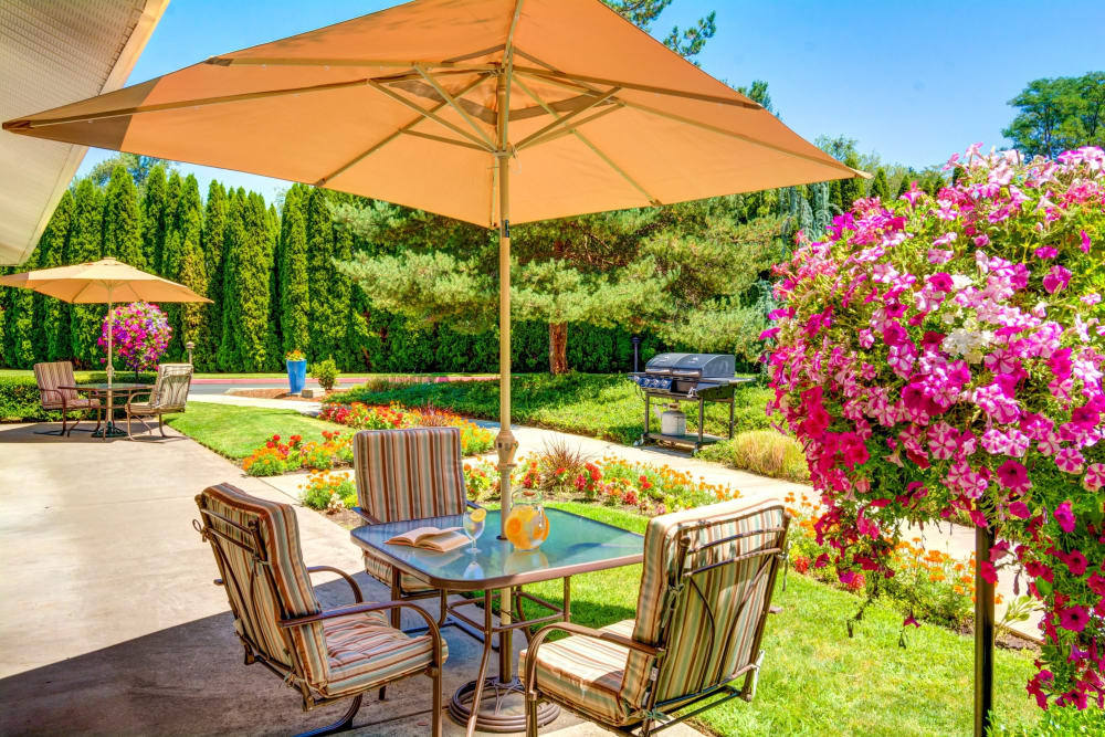 Table with an umbrella for outdoor dining or relaxing on the garden veranda at The Suites Assisted Living and Memory Care in Grants Pass, Oregon