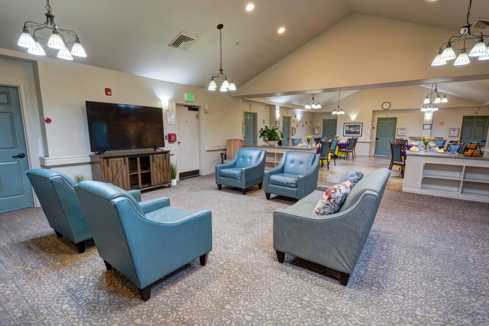 Resident lounge with armchairs and a large flat screen TV at Timberwood Court Memory Care in Albany, Oregon