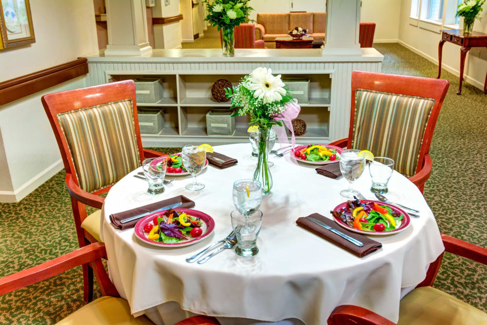 Table set with garden salads in the community dining room at Timberwood Court Memory Care in Albany, Oregon