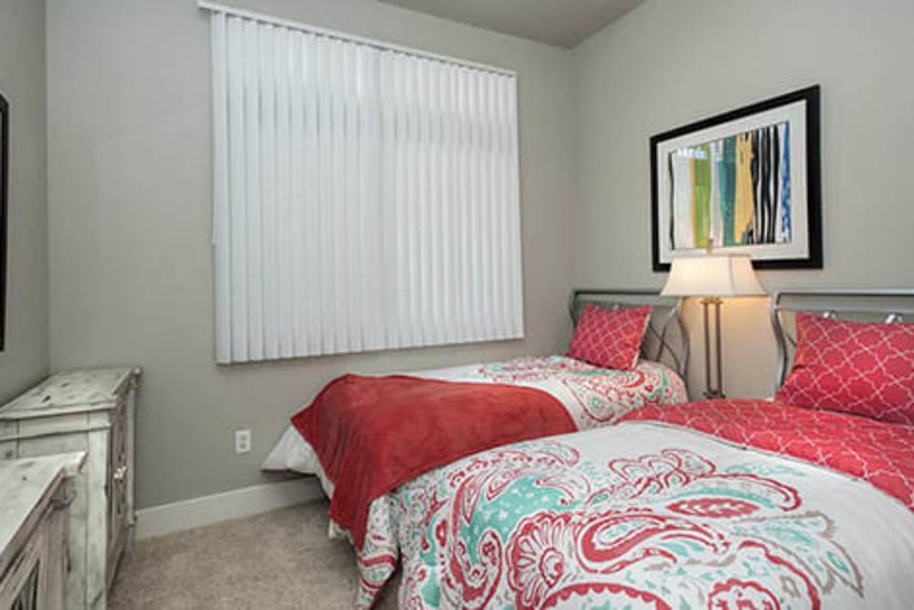 Model bedroom with twin beds and plush carpeting at Octave in Davis, California