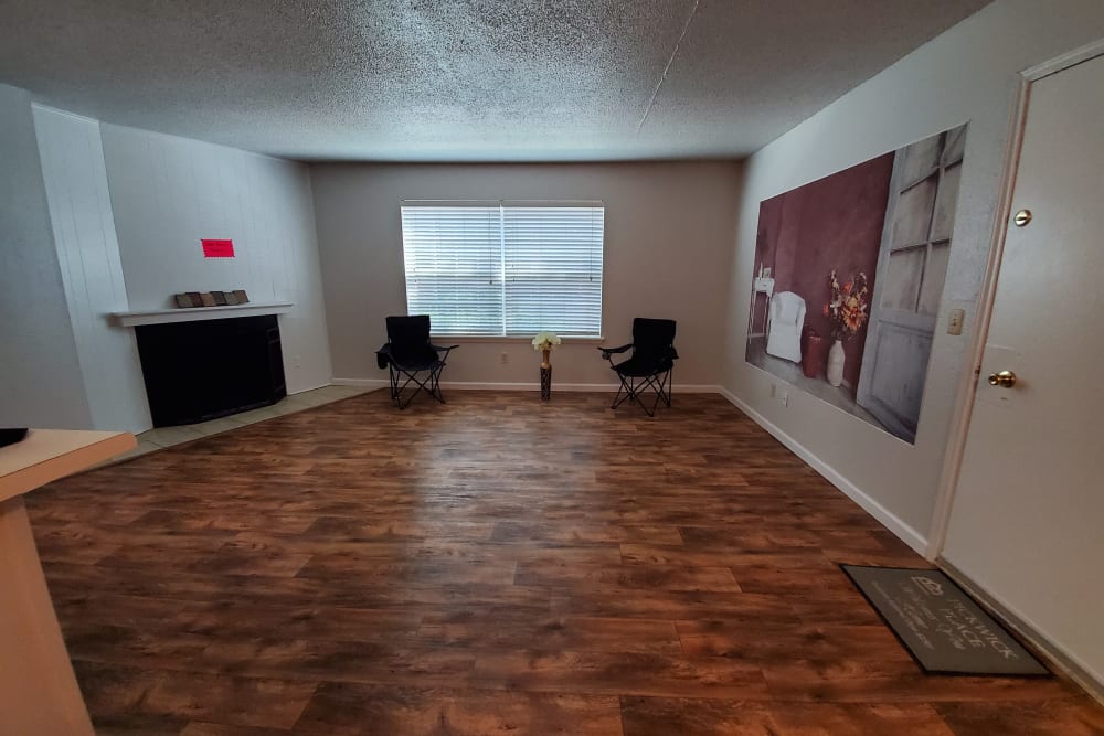 Model apartment living room with a fireplace and hard wood floors at Pickwick Place in Oklahoma City, Oklahoma