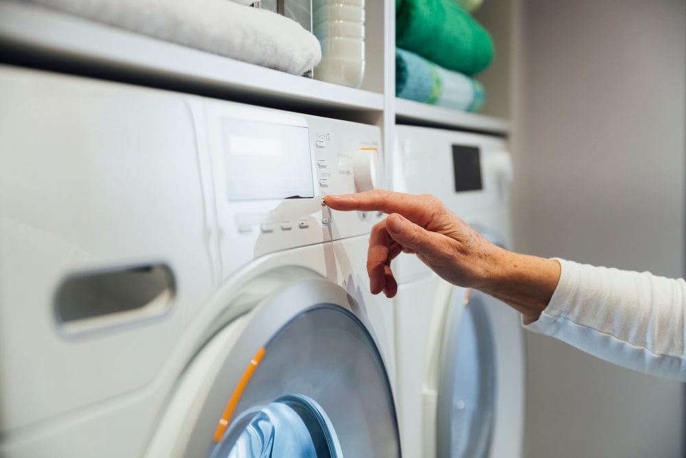 Resident starting a load of laundry in her full-size washer and dryer at Lotus Apartments in Martinez, California