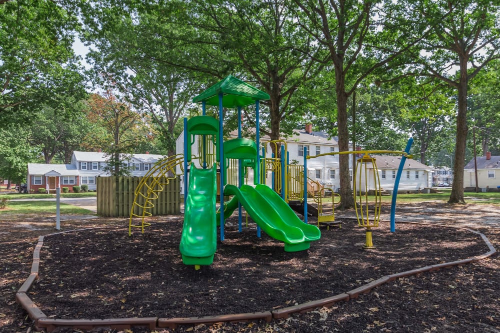 A playground surrounded by trees at Cottage Grove Apartments in Newport News, Virginia
