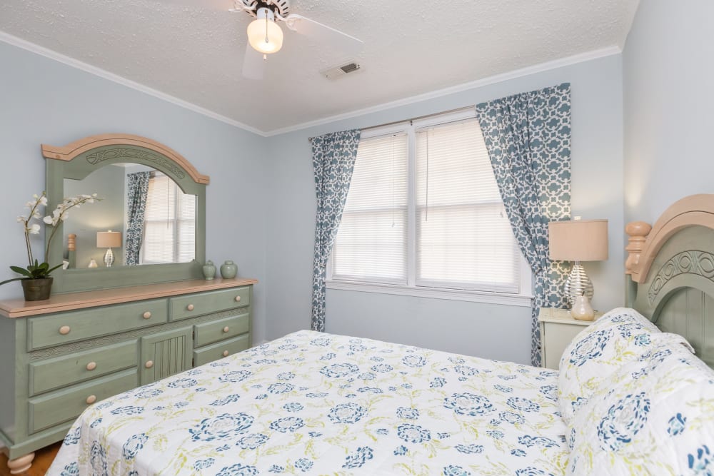 A bed and dresser in a model apartment bedroom at Cottage Grove Apartments in Newport News, Virginia