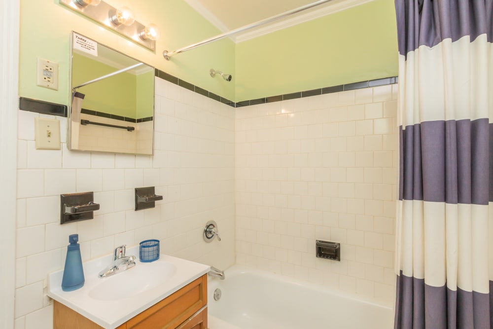 A tiled bathroom with a full-sized bathtub at Cottage Grove Apartments in Newport News, Virginia