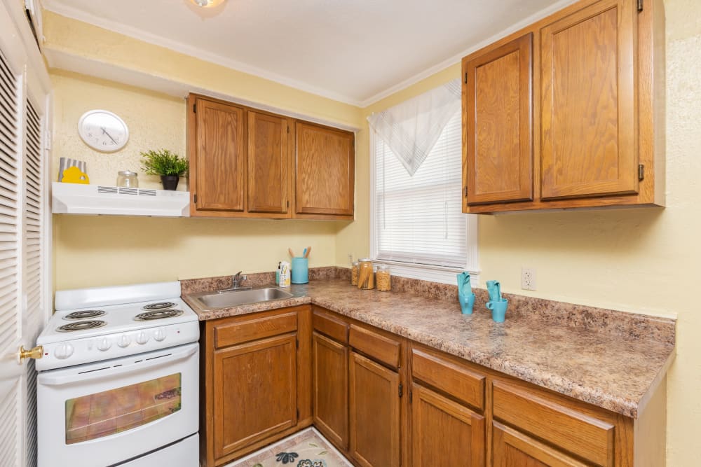 Wood cabinets and white appliances in an apartment kitchen at Cottage Grove Apartments in Newport News, Virginia
