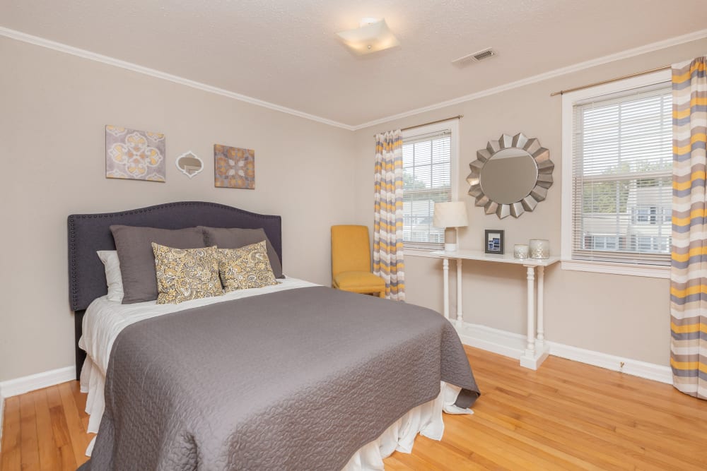 A king-sized bed and two windows in an apartment bedroom at Cottage Grove Apartments in Newport News, Virginia